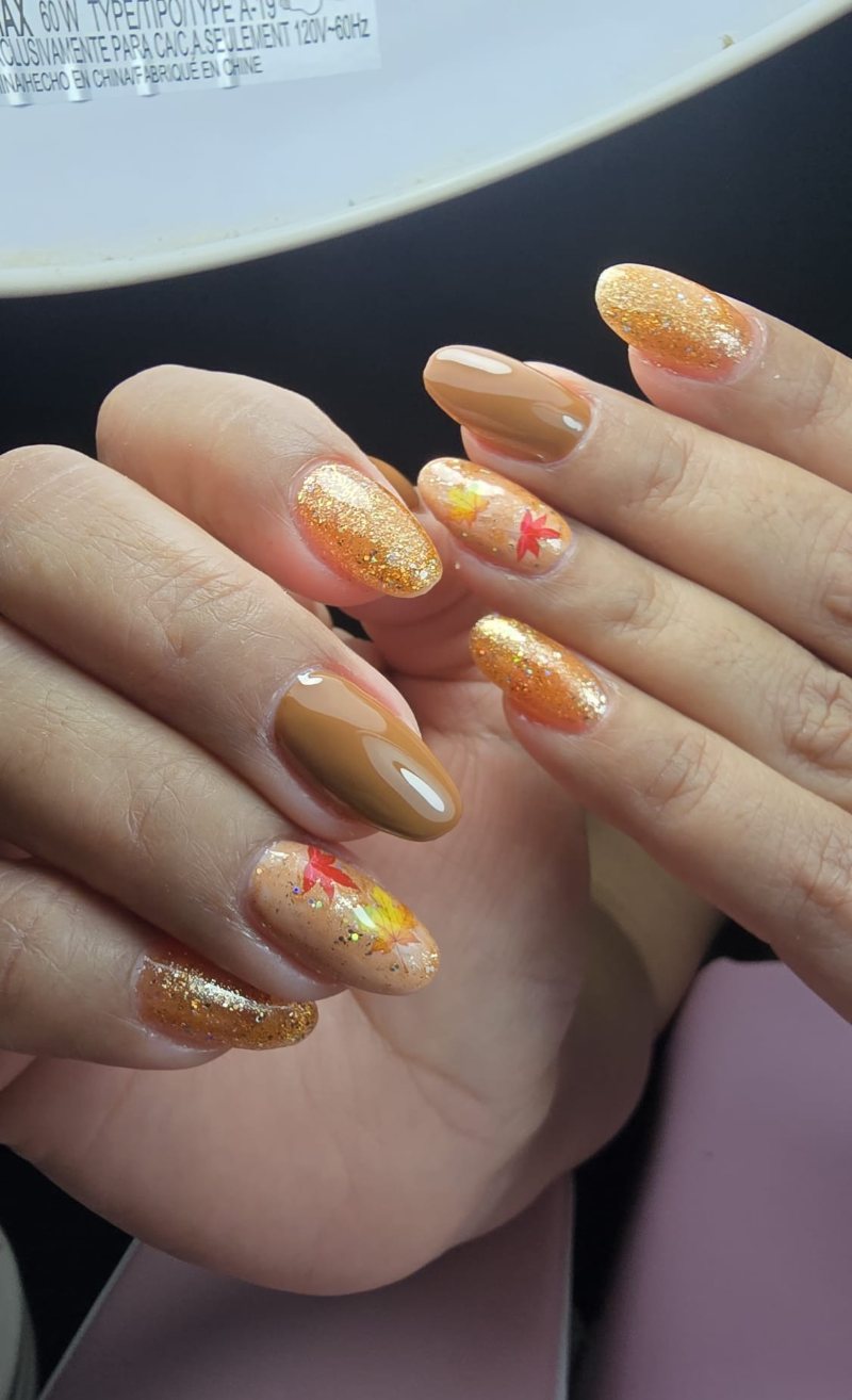 Uñas en tonos caramelo y cobre con glitter y hojas de otoño